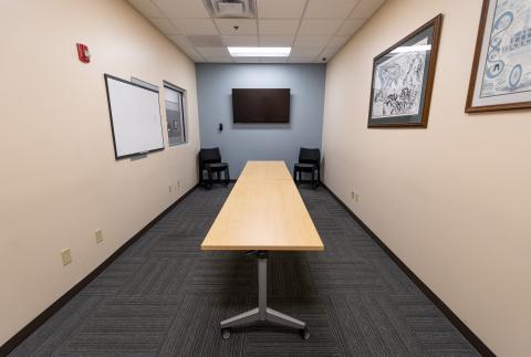 Small conference room with two tables, a TV, and chairs.