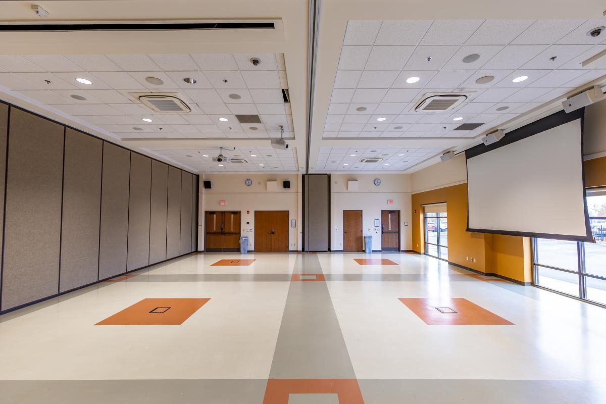 A large meeting room with a 16' screen and windows.